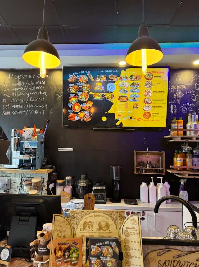 Cafe Tehran menu board, a coffee machine, and various food items.